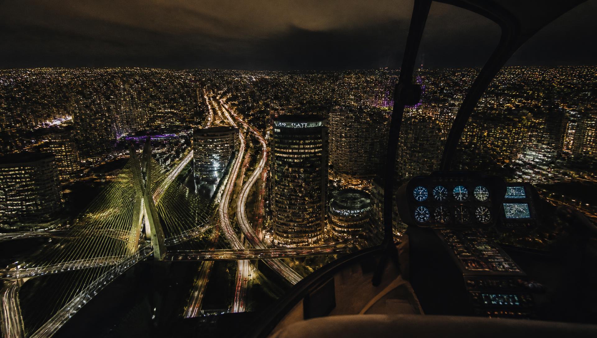 Night view of the São Paulo skyline from a helicopter cockpit
